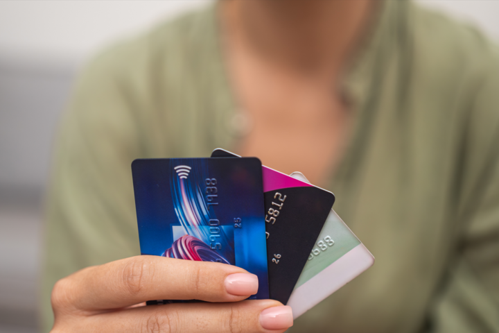 Close-up: Woman hand grasps stack of credit cards, what is credit card stacking, symbolizing online payments, shopping